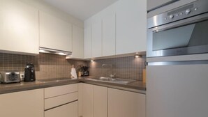 Una cucina moderna con mobili bianchi, un forno in acciaio inossidabile, una macchina per il caffè e un tostapane.
