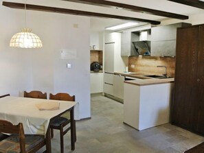 A compact kitchen with a central island, a dining area with a table and chairs, and a pendant light fixture.