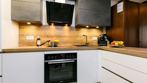 A modern kitchen with a built-in oven, a sink, and a countertop with a pot and utensils.