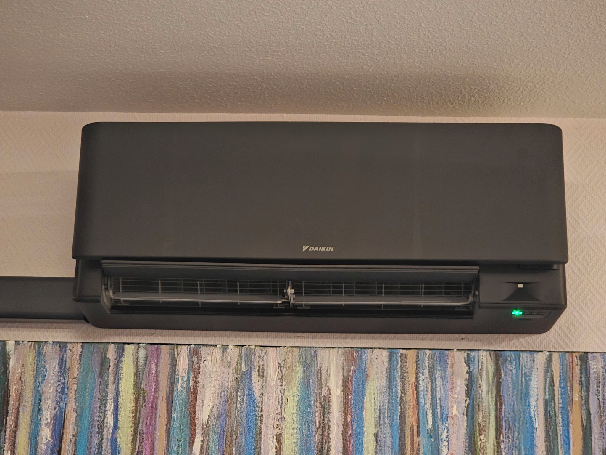 Un climatiseur Daikin noir fixé au mur.