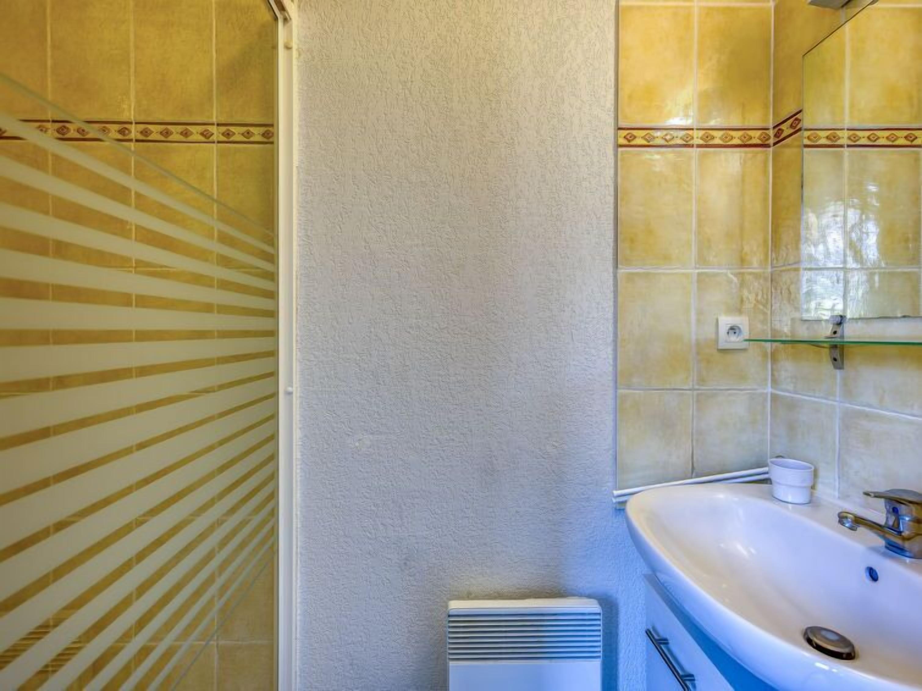 A bathroom with a white shower curtain, a sink with a mirror, and yellow-tiled walls.