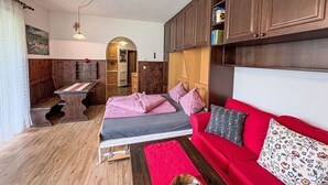 Une pièce confortable avec un lit, un canapé rouge, des meubles en bois et un petit bureau avec une chaise.