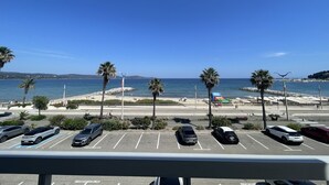 Ein Parkplatz mit mehreren Autos, ein Strand mit Palmen und ein klarer, blauer Himmel.