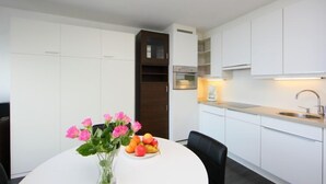 Een moderne keuken met witte kasten, een ingebouwde oven en een eethoek met een tafel gedekt voor twee personen.