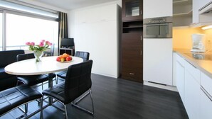 Een moderne hotelkamer met een zithoek, een keuken en een groot raam.