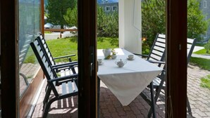 A balcony with a table set for tea, chairs, and a view of a mountain landscape.