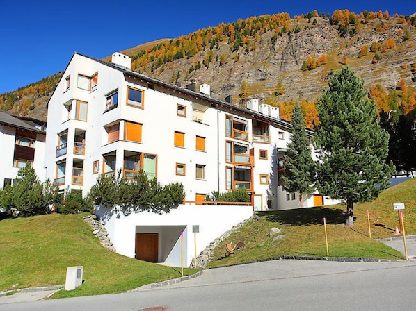 Un hôtel à plusieurs étages doté de balcons, d’un parking et situé au pied d’une colline.