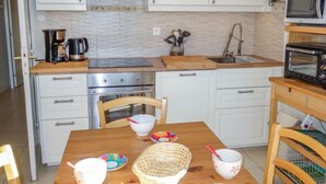 A kitchen with white cabinets, stainless steel appliances, a wooden table, and a microwave.