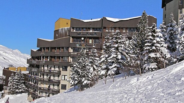 Ein mehrstöckiges Hotel mit Balkonen und einer verschneiten Landschaft.