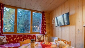 Ein gemütliches Blockhauskabinenzimmer mit Holzvertäfelung, einem Esstisch mit Tellern, Tassen und einem Brotkorb.