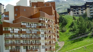 Ein mehrstöckiges Hotel mit Balkonen, einer Seilbahn und einer Bergkulisse.