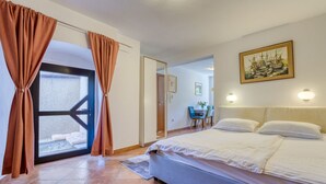 A hotel room with a bed, curtains, a painting, and a view through a door. - Lovrano by Interhome (Lovran)