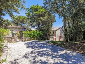 A rustic stone building with a gravel driveway leading to a wooden gate.