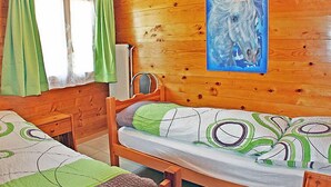Ein Holzhütten-Zimmer mit zwei Betten, einem Heizkörper und einem Gemälde von einem Pferd.