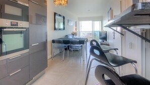 Uma cozinha moderna com eletrodomésticos de aço inoxidável, sala de jantar com lustre e vista para o exterior.