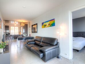 A modern living room with a leather sofa, a dining area with a bar, and a bedroom with a bed.