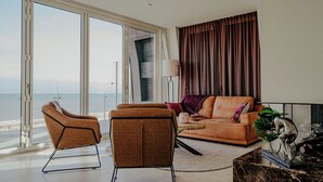 Un salon moderne doté d’une grande porte-fenêtre coulissante donnant sur un balcon avec vue sur la mer.