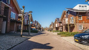 A residential street with modern houses, a paved walkway, and parked cars. - Dorregeest by Interhome (Uitgeest)