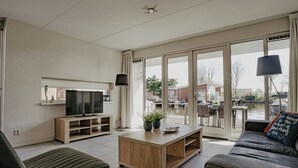 A modern living room with a TV, wooden coffee table, and a sofa. - Dorregeest by Interhome (Uitgeest)