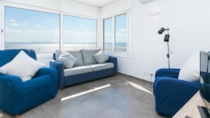 A modern room with a large window, a sofa, a TV, and an air conditioning unit.