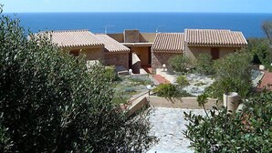 Une propriété située sur la côte, avec des bâtiments aux toits de tuiles en terre cuite, un chemin pavé de pierres et une vue sur la mer.