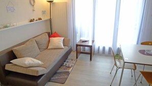 A living room with a sofa, a small table, and a dining area with chairs.