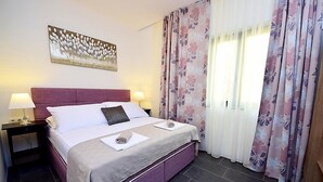 A hotel room with a bed, two nightstands, a painting, and floral curtains. - Molo Lozna by Interhome (Brač/Postira)