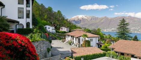 Una zona residencial en una ladera con casas, un muro de piedra y vistas a un lago y montañas.
