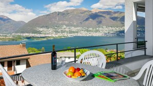 Ein Balkon mit Tisch, einer Weinflasche und einer Obstschale.