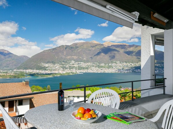 A balcony with a table, a bottle of wine, and a bowl of fruit. - Residenza Miralago Apt. A8 by Interhome (Piazzogna)