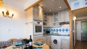 A compact kitchen with white cabinets, a microwave, an oven, and a washing machine. - Le Slalom (Val Claret) by Interhome (Tignes)