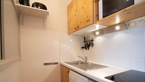 A compact kitchen with white cabinetry, a built-in dishwasher, a stove, and a sink. - Le Hameau du Borsat (Val Claret) by Interhome (Tignes)