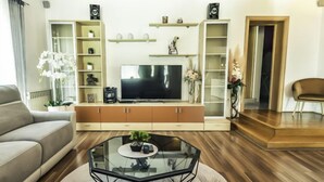 Uma sala de estar moderna com um sofá, uma mesa de centro de vidro, uma televisão e estantes embutidas.