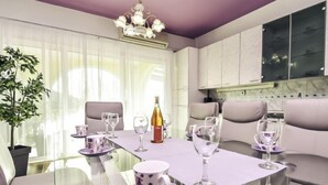 Uma área de jantar moderna com mesa de vidro, cadeiras brancas e um lustre.
