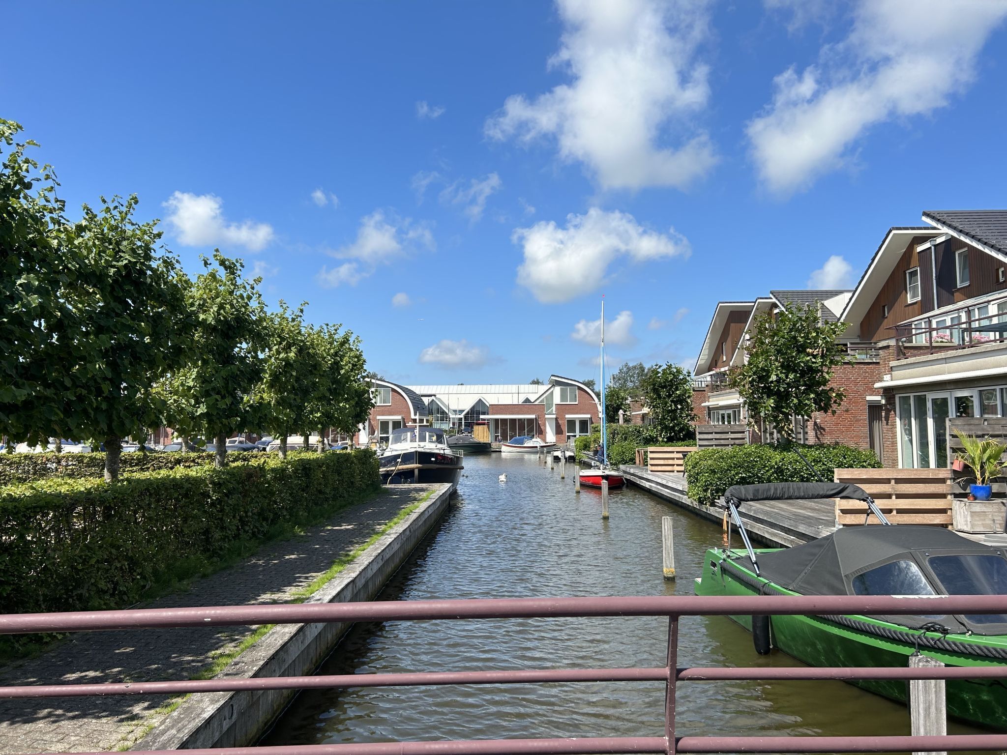 A canal with boats, a bridge, and modern houses with large windows.