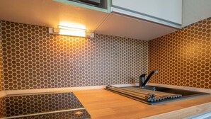 Une cuisine moderne avec un revêtement mural à motifs en nid d’abeille, un plan de travail en bois et un évier encastré.