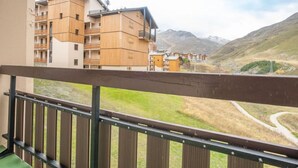 Un balcon donnant sur un paysage montagneux et une rangée de bâtiments en bois.