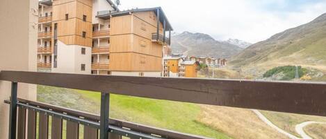 A balcony with a view of a mountainous landscape and a row of wooden buildings.