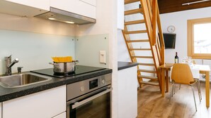 Eine moderne Küche mit Edelstahlgeräten, einer Holztreppe und einem Essbereich mit Tisch und Stühlen.