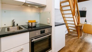 Eine moderne Küche mit Edelstahlgeräten, einer Holztreppe und einem Essbereich mit Tisch und Stühlen.