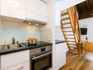 Een koelkast, een oven, een vaatwasser, kookgerei, borden en bestek