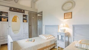 Ein Schlafzimmer mit zwei Betten, einem Kleiderschrank, einem Nachttisch und einer Wandlampe.