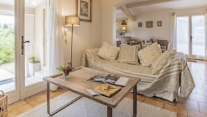 Ein gemütliches Wohnzimmer mit einer Couch, einem Couchtisch und einer Lampe. Eine Tür führt zu einem Balkon.