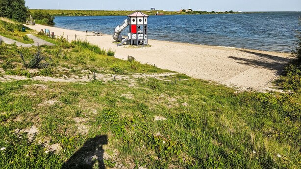 Ein Strand mit einer kleinen Struktur, möglicherweise einem Rettungsturm, in der Nähe des Wassers.