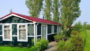 Ein zweistöckiges Haus mit rotem Dach, weißem Zierdekor und einer Auffahrt mit Kies, die zur Haustür führt.