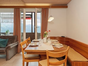 A dining area with a wooden table set for four, surrounded by wooden chairs with cushioned seats.