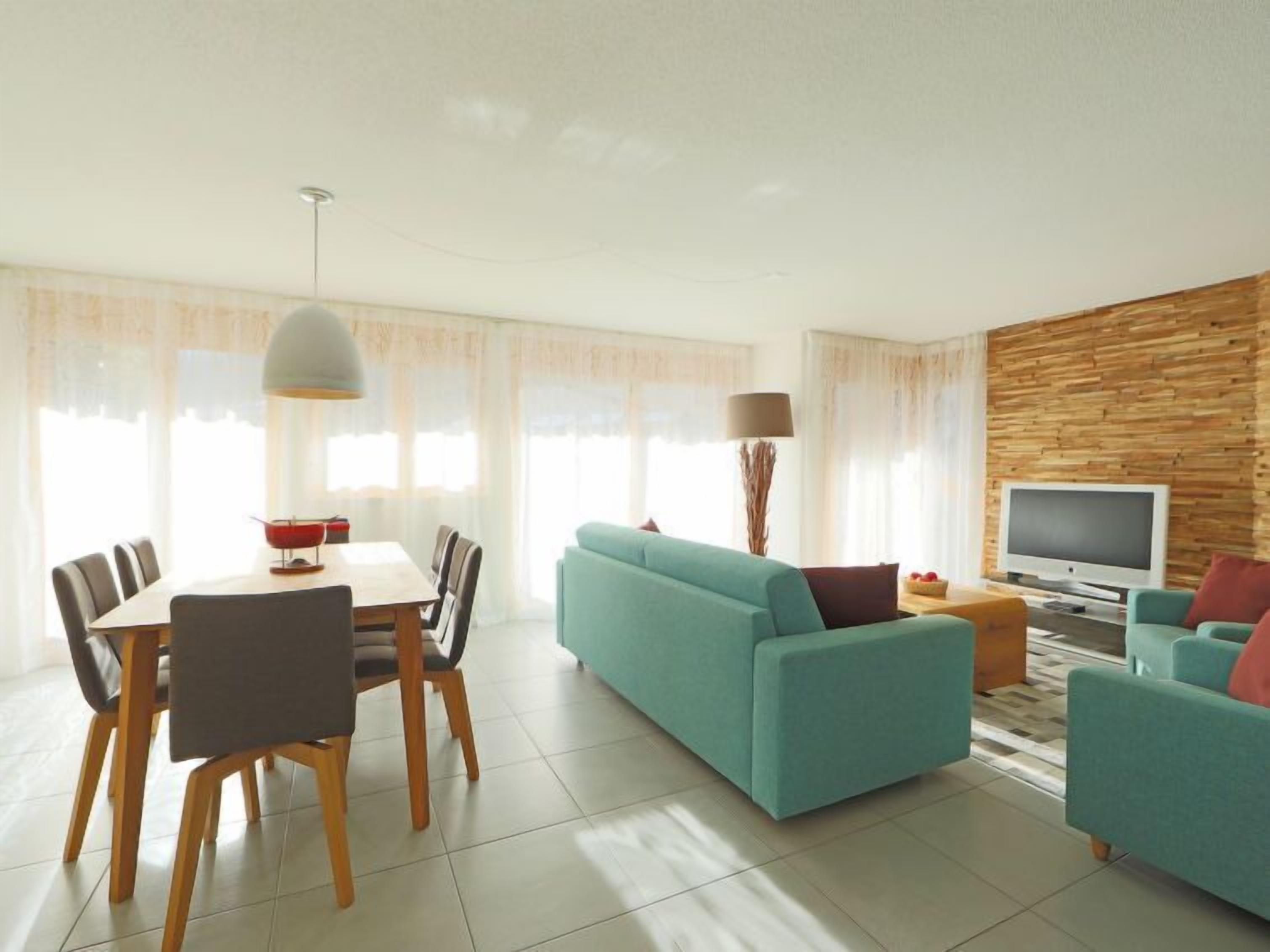 A modern living room with a sofa, TV, and dining area.