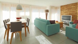 Una sala de estar moderna con sofá, televisor y comedor.