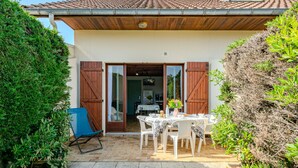 A patio area with a table and chairs, a wooden door, and a tiled roof. - Vacation home Sicard by Interhome (Mimizan)