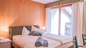 Un lit double avec une tête de lit en bois, une table de chevet avec une lampe et une fenêtre avec des rideaux.